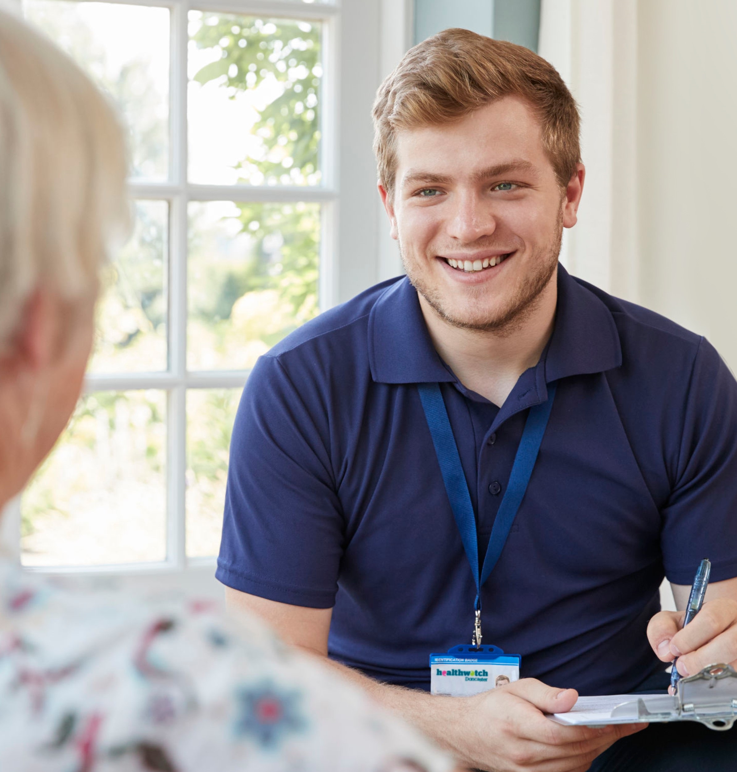 Male holding a clipboard smiling to another person