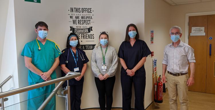 Five healthcare professionals stood up wearing a mask