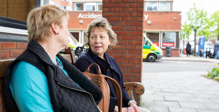 Two women sat down outside a hospital