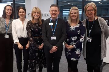 A group of people stood up smiling at the camera