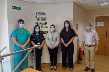 Five healthcare professionals stood up wearing a mask