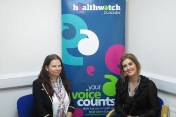 Two women sat down smiling at the camera