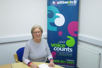 Woman holding a pen with papers sat behind a desk