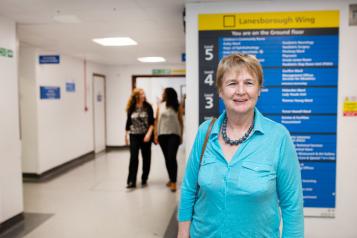 Woman standing infront of a hospital sign that shows all the different departments