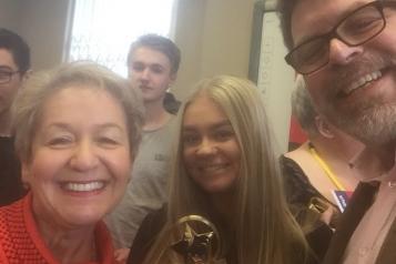 A group of people stood up smiling at the camera holding a trophy
