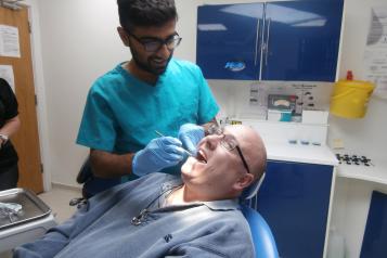 Patient sitting in dentist chair with dental treatment taking place