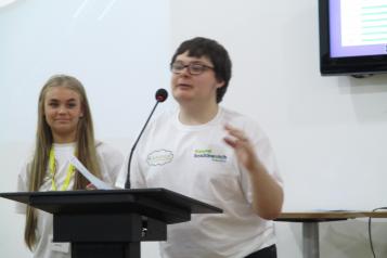 Young female and young male speaking from a podium