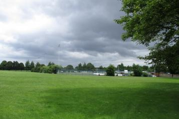 A field with a outdoor football area in the background